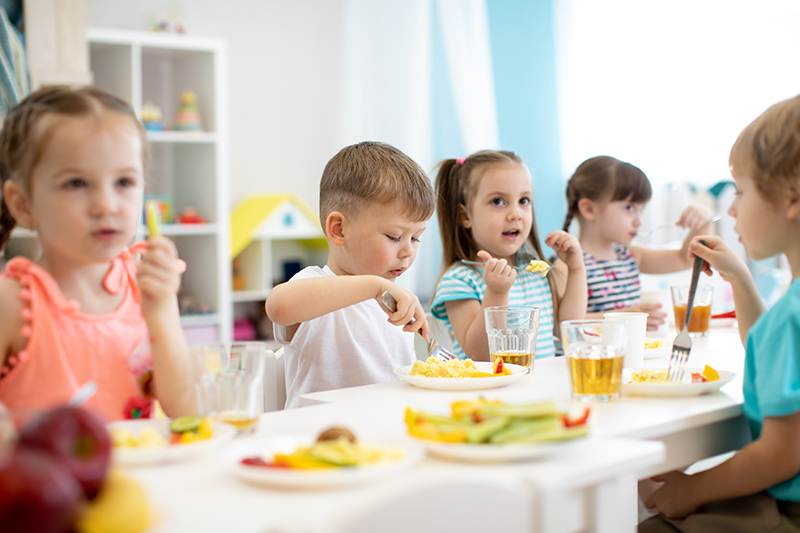 Group of preschool kids have a lunch in daycare. Children eat healthy food in kindergarten